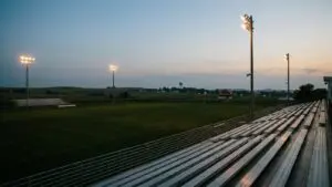 Nebraska high school football stadium at dusk, stadium lights turning on