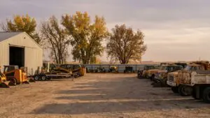 Landscaping equipment yard on the edge of Omaha with skid steers and trucks parked on gravel in autumn light